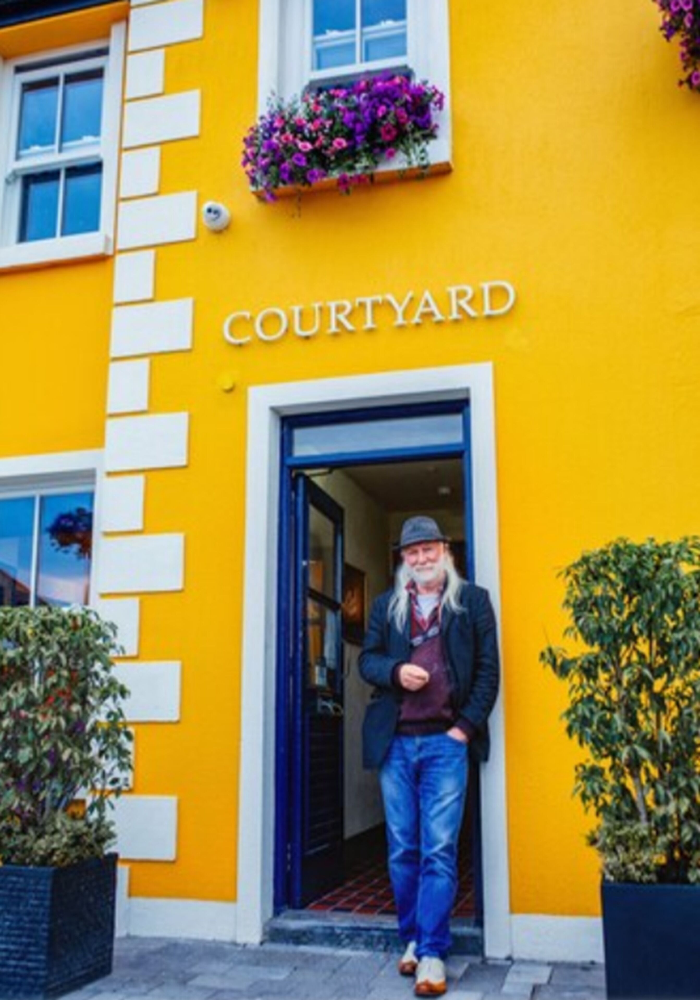 Um edifício com fachada amarelo brilhante e uma placa com a inscrição 'COURTYARD'.