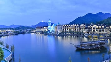 Um hotel às margens do rio, com estilo arquitetônico tradicional, com várias varandas e um barco atracado no cais.