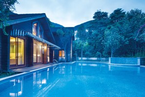 Una casa moderna con piscina, fachada de madera y ventanas amplias.