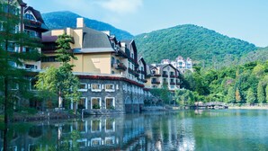 A lakeside hotel with traditional architecture, a stone bridge, and a mountain backdrop. - The Interlaken OCT Hotel Shenzhen (Shenzhen)