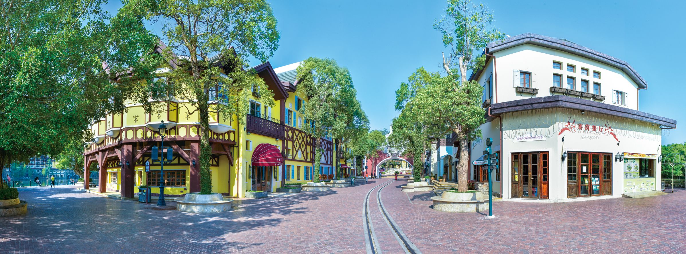 Une rue bordée d’immeubles, avec un tramway et des arbres.