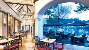 A restaurant with outdoor seating overlooking a body of water, featuring a checkered floor and red cushioned chairs. - The Interlaken OCT Hotel Shenzhen (Shenzhen)