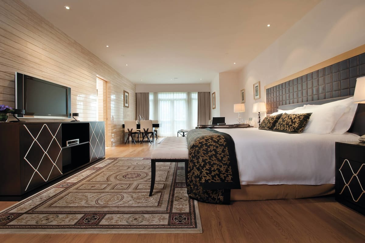 Een hotelkamer met een groot bed, een televisie, een bureau en een zithoek.