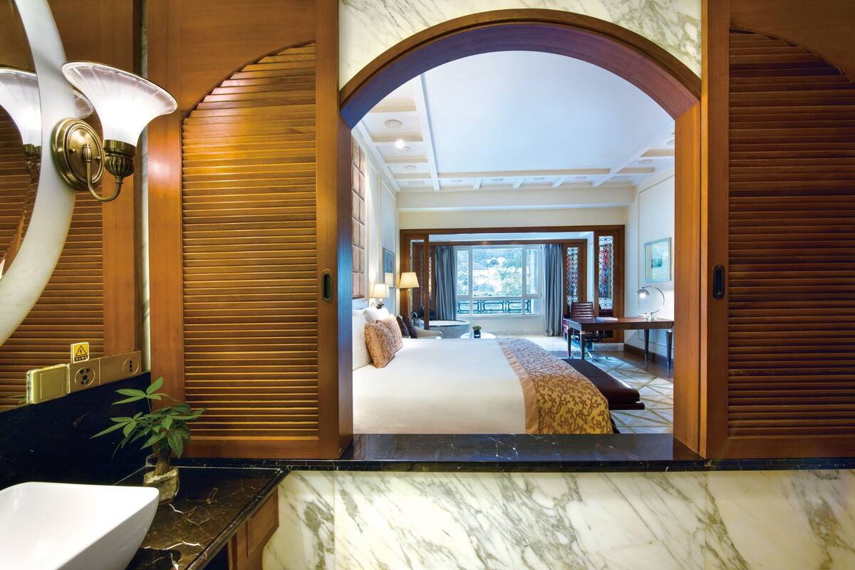 Een hotelkamer met een groot bed, een bureau en uitzicht op de omgeving door een groot raam.
