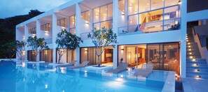 Un edificio moderno de varios pisos con piscina, mobiliario exterior y una escalera que conduce a las plantas superiores.