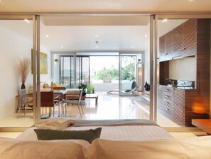 A modern bedroom with a large bed, a dining area, and a view of the outdoors.