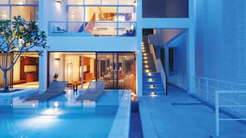 A modern building with a pool, outdoor seating, and a staircase leading to an upper level.