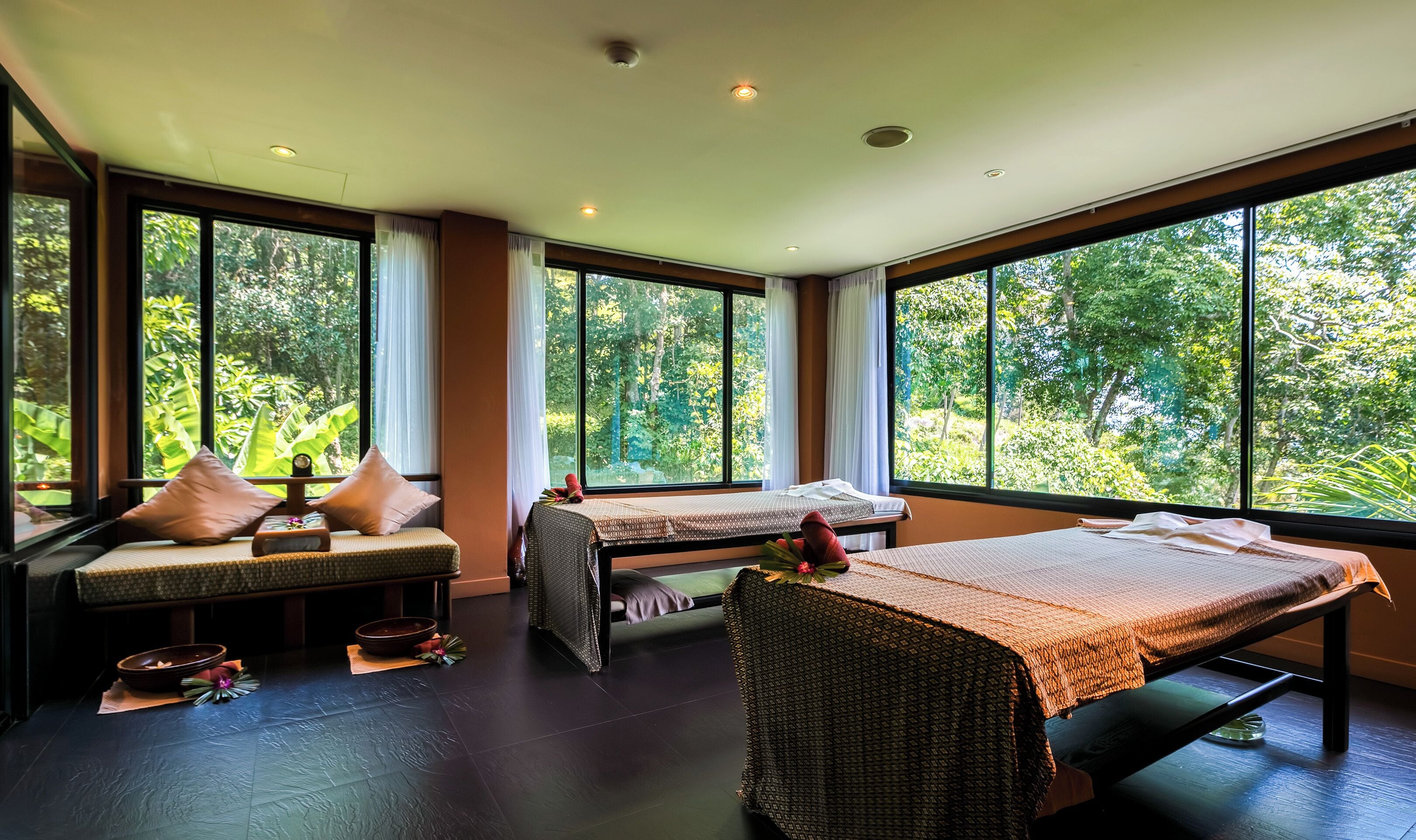 Una habitación con dos camas, ventanas amplias y vista a la vegetación.