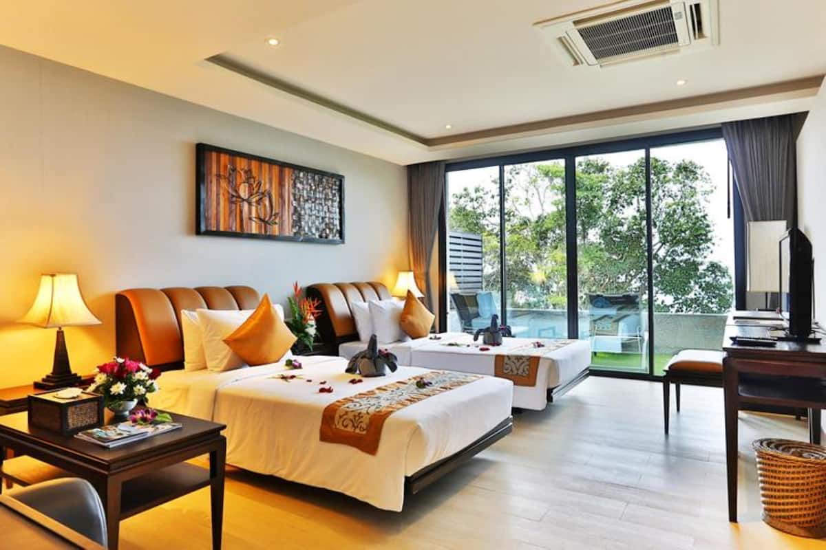 A hotel room with two beds, a desk, a chair, a TV, and a large window with a view of trees.