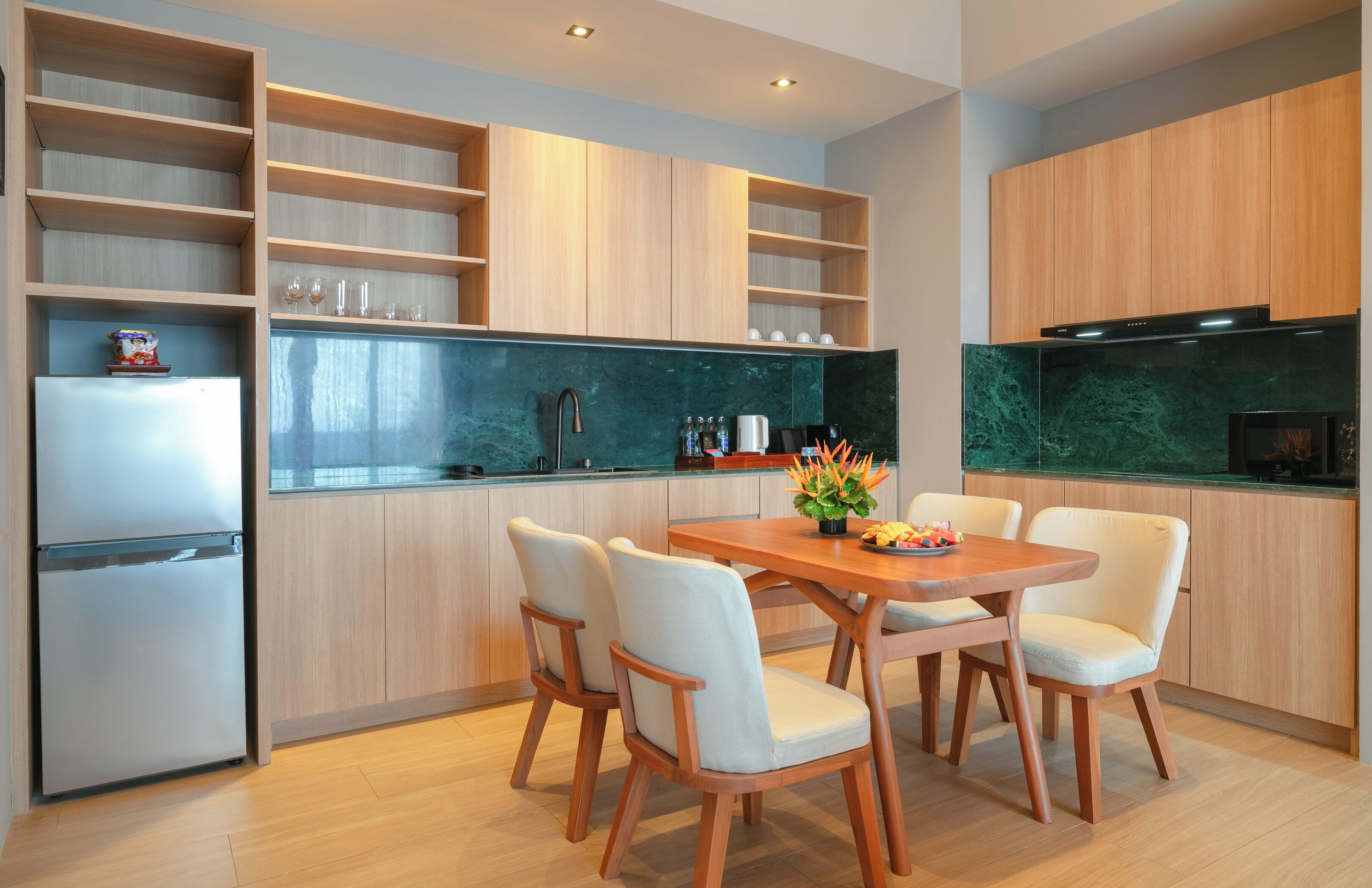 A modern kitchen with wooden cabinets, a stainless steel refrigerator, and a dining table with chairs.