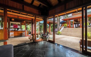 A modern hotel lobby with a reception desk, seating area, and a view of the outdoor staircase and garden.
