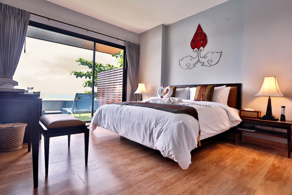 A bedroom with a bed, bedside tables, a desk, and a view of the outdoors.