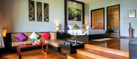 A hotel room with a bed, a sofa, a coffee table, and a painting on the wall.