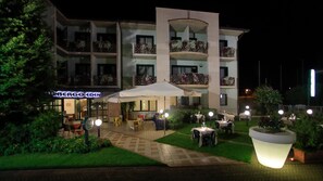 A hotel with outdoor seating, a sign reading "BERGO EDEN," and multiple balconies with flower boxes. - Eden (Valeggio sul Mincio)