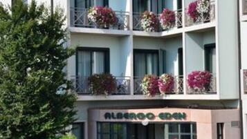 A hotel with a modern facade, multiple balconies with flower boxes, and a well-maintained outdoor seating area.