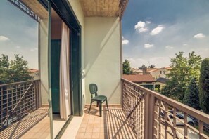 A balcony with a chair, a door, and a view of the surrounding buildings. - Eden (Valeggio sul Mincio)
