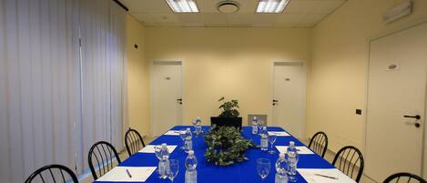 A conference room with a blue table, chairs, water bottles, and a plant.