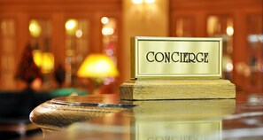 Une plaque portant l’inscription « CONCIERGE », fixée sur un socle en bois, est placée sur une surface réfléchissante.
