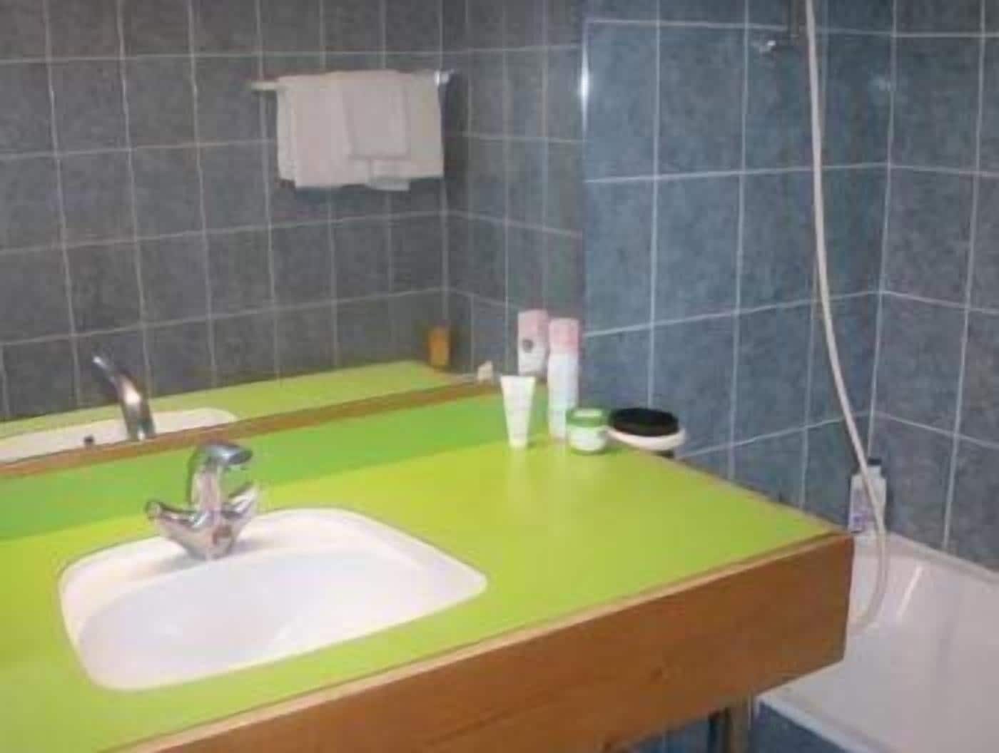 A bathroom with a green sink, a mirror, and a towel hanging on the wall.