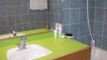 A bathroom with a green sink, a mirror, and a towel hanging on the wall.
