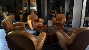A modern lobby with leather armchairs, a glass coffee table, and a reception desk. - Hotel Dupleix (Quimper)