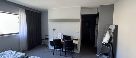 A hotel room with two beds, a desk with a chair, a computer, and a mirror.