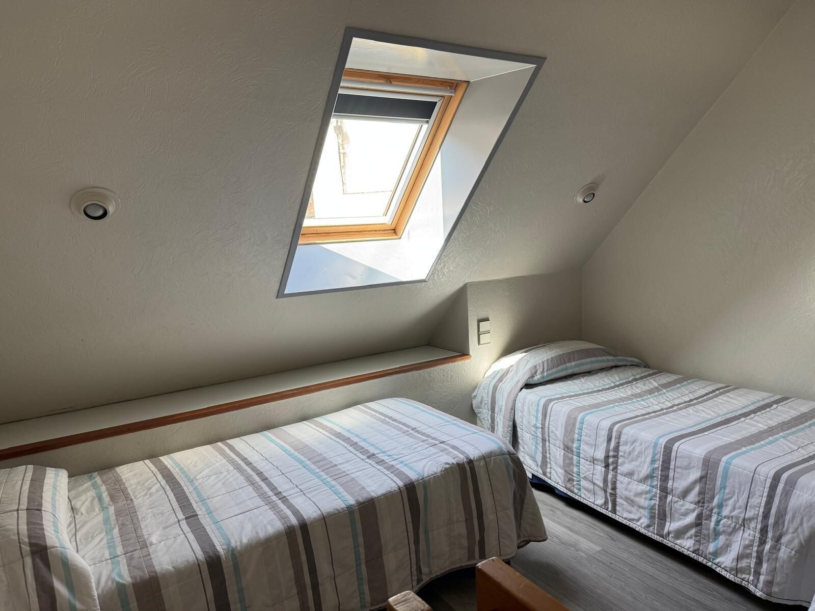 Un apartamento pequeño de una habitación con dos camas, un tragaluz y techo inclinado.