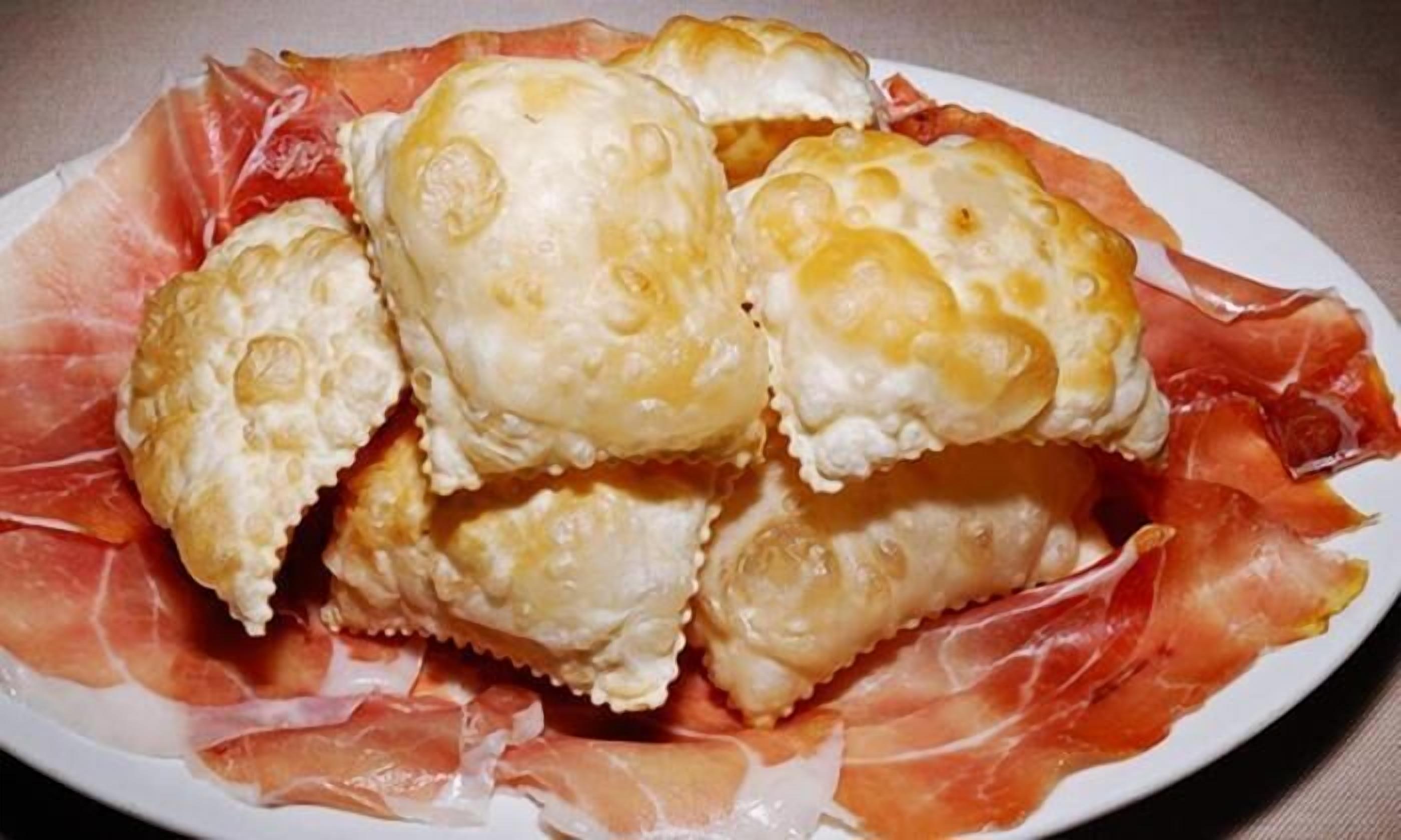 A plate of pastries with a creamy filling and a red meat garnish.