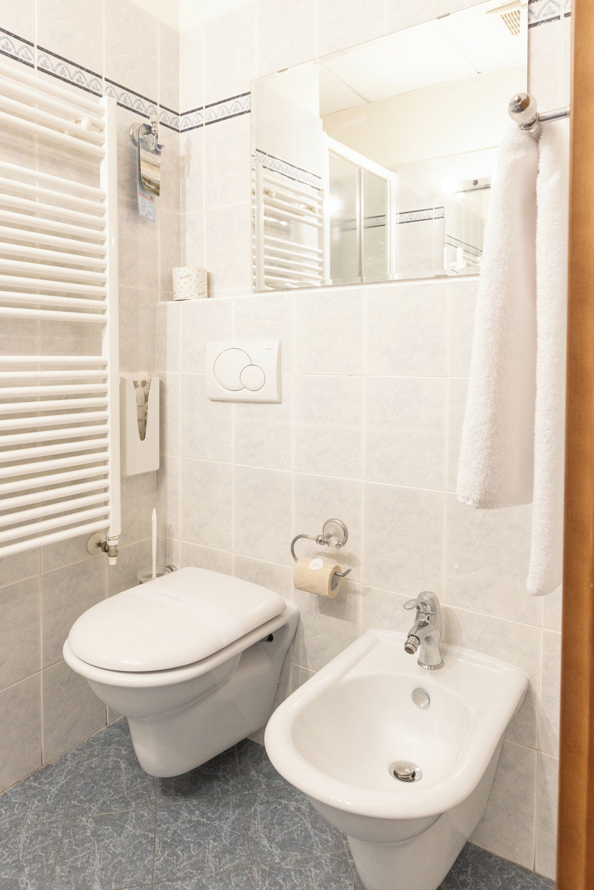 A bathroom with a toilet, bidet, and sink, all in white.