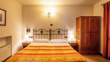 Habitación de hotel con cama, dos lámparas de noche, armario de madera y aplique de pared.