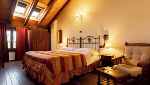 A room with a wooden ceiling, a bed with a patterned bedspread, two bedside lamps, a wooden chair, and a small table. - Locanda del Mulino (Maranello)