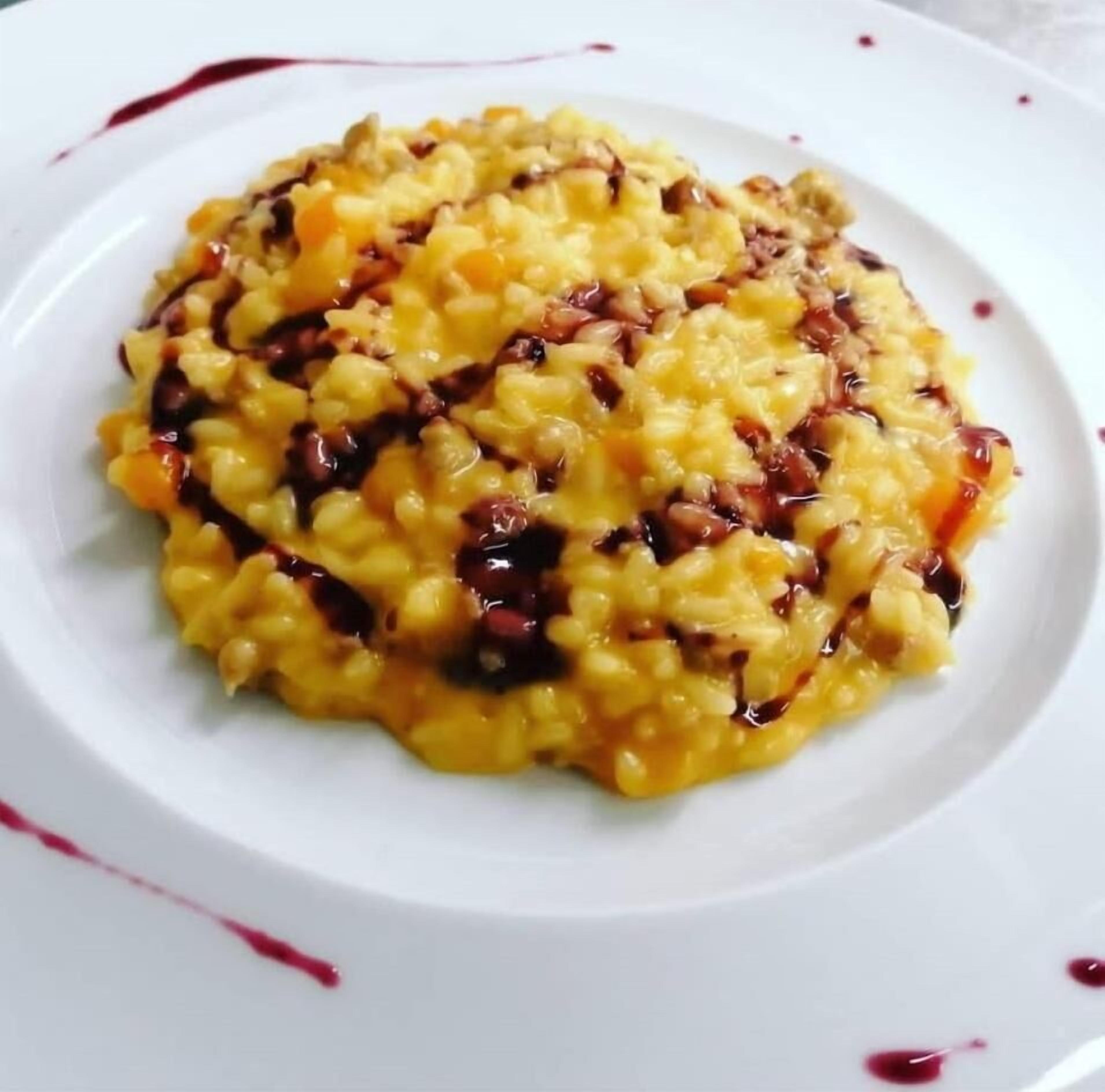 A plate of risotto with a red sauce drizzle.