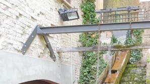 A narrow staircase with a wooden handrail, leading to a window with a view of a garden. - Locanda del Mulino (Maranello)