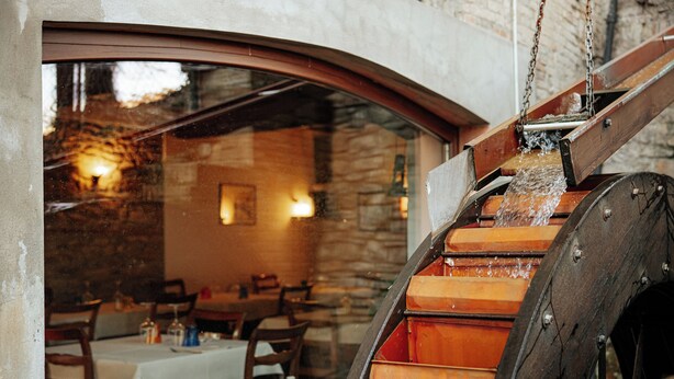A rustic interior with stone walls, wooden furniture, and a water wheel. - Locanda del Mulino (Maranello)