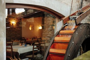 Un intérieur rustique avec des murs en pierre, des meubles en bois et une roue à eau.
