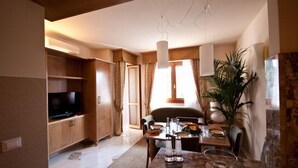 A cozy living room with a television, wooden cabinets, a dining table set for two, and a large plant. - Antella Residence (Bagno a Ripoli)