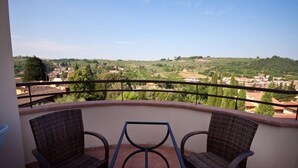 A balcony with wicker chairs and a view of a hilly landscape with buildings. - Antella Residence (Bagno a Ripoli)
