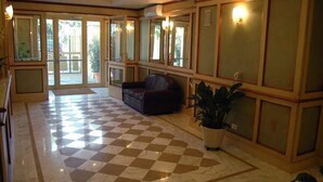 A spacious lobby with a checkered floor, a leather sofa, and a potted plant. - Antella Residence (Bagno a Ripoli)