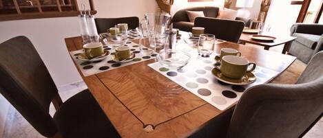 Una mesa de comedor dispuesta con varias tazas y platillos, una jarra y un jarrito de vidrio.