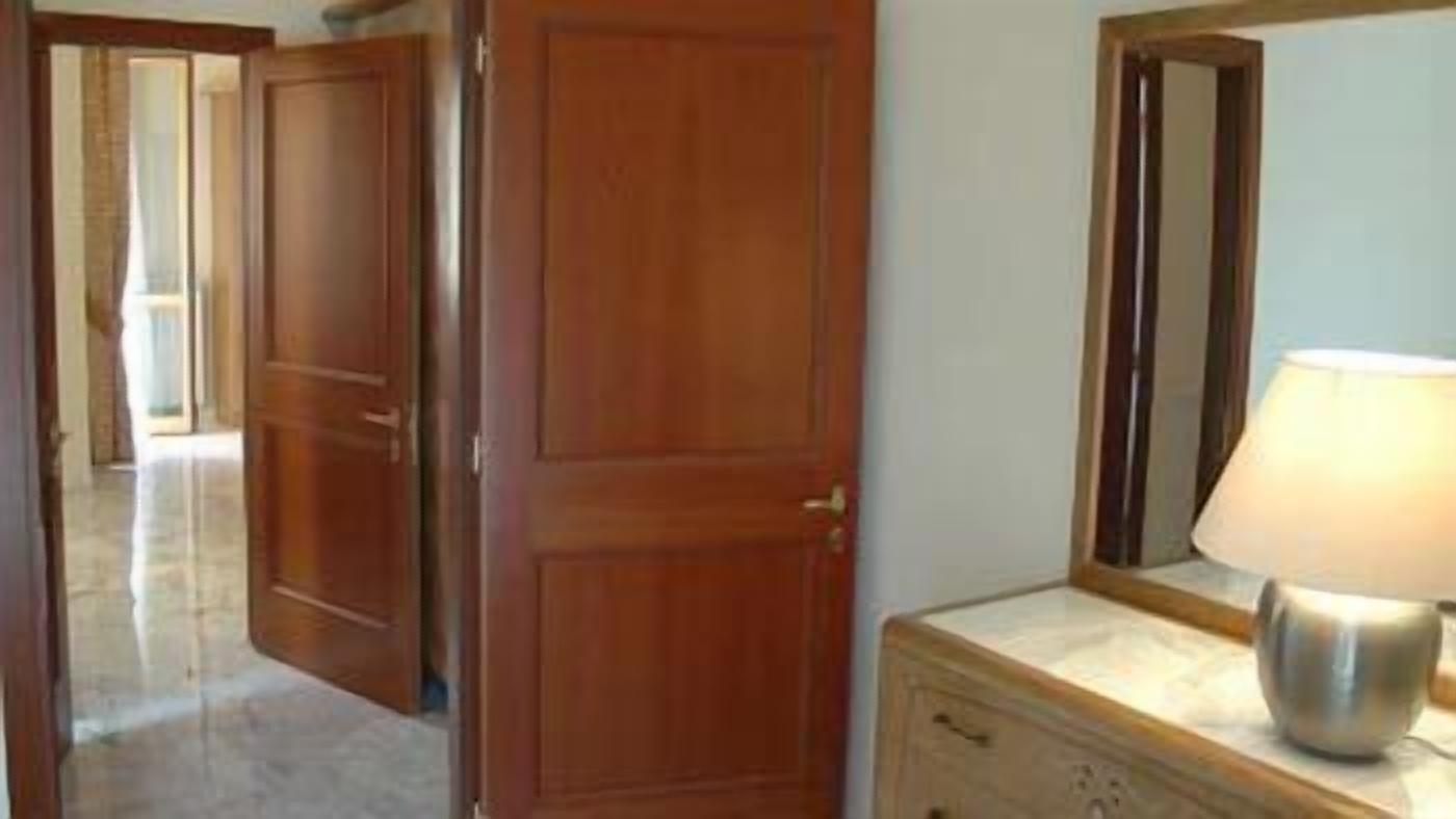 A hallway with wooden doors, a marble-topped dresser, and a mirror.