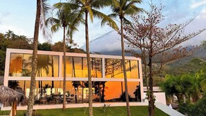 Un edificio moderno de dos pisos con grandes ventanales que reflejan el paisaje circundante.
