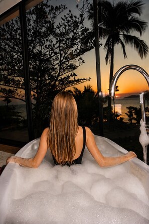 A person relaxing in a bathtub with a view of the sunset and palm trees. - DPNY Beach Hotel & SPA Ilhabela (Ilhabela)