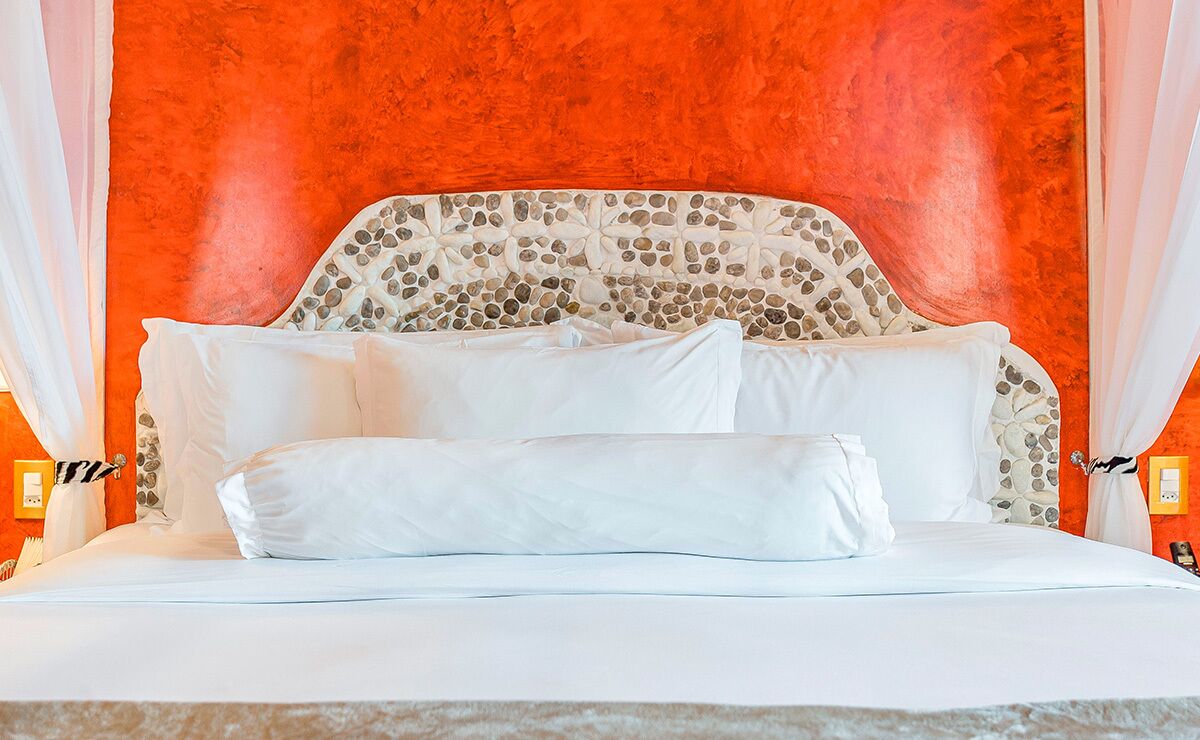 A bed with white linens and a headboard with a mosaic pattern.