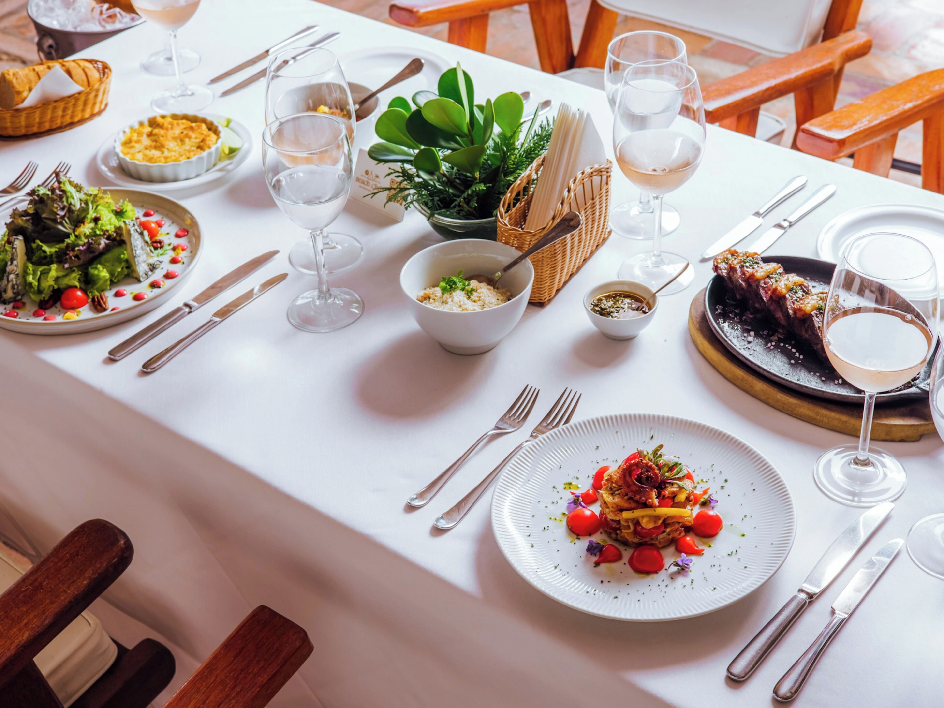 Une table à manger dressée avec différents plats, verres et couverts.