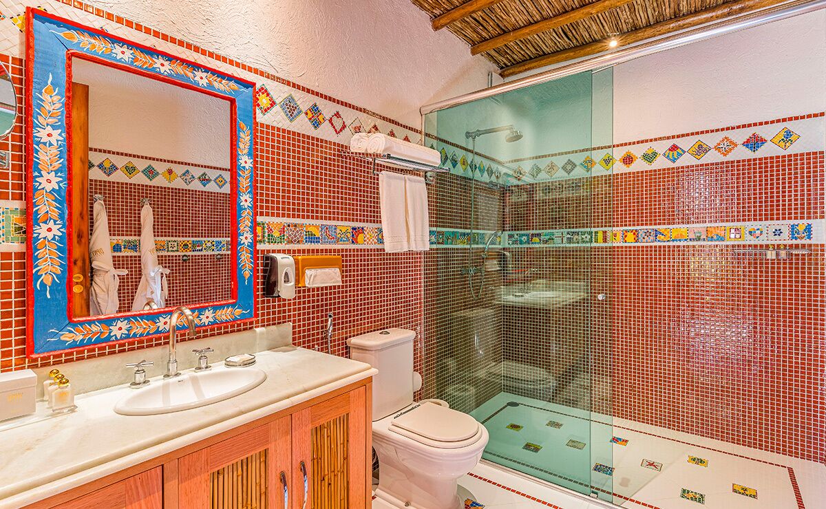 Une salle de bain avec deux éviers, des toilettes et une douche séparée par une paroi en verre.