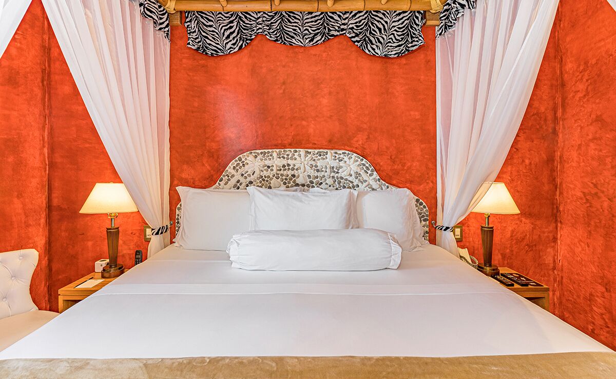 A bed with white linens, a zebra-patterned headboard, and white curtains.