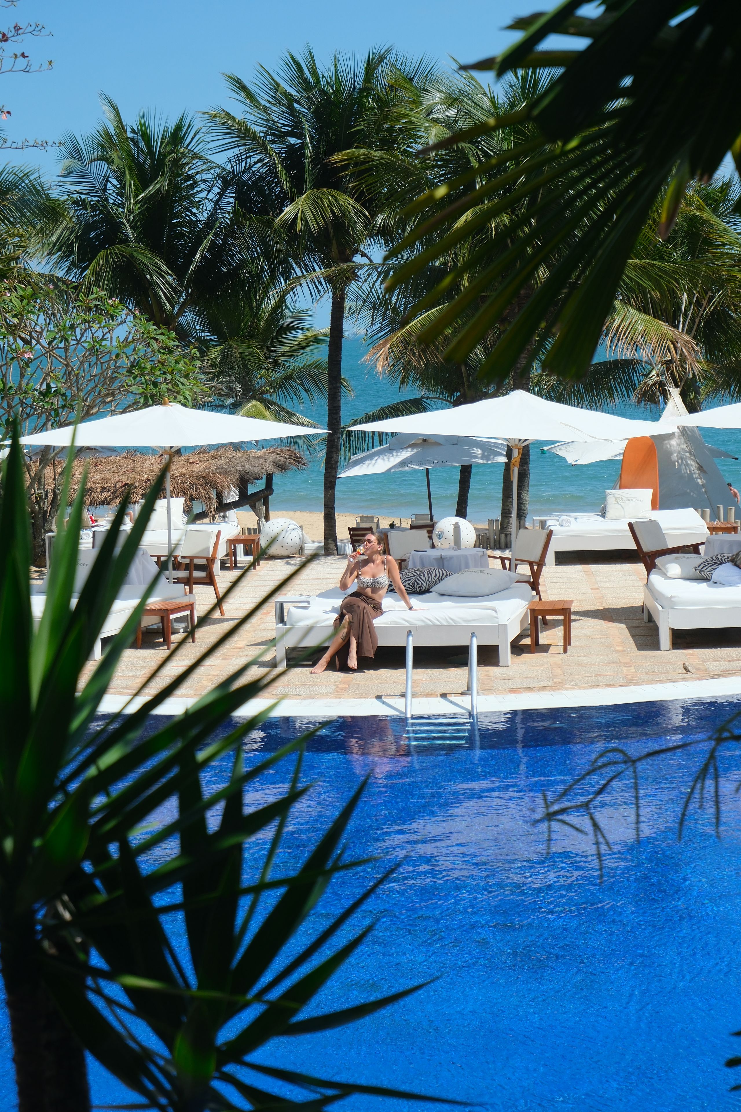 Un área junto a la piscina con sillones de descanso, sombrillas y vistas al mar.