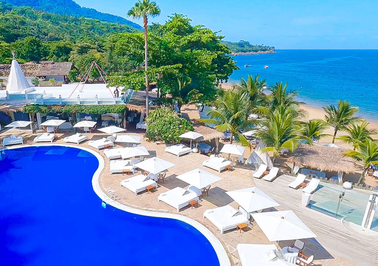 Un resort con una gran piscina, tumbonas y una zona de playa.