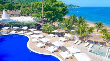 Un resort con una gran piscina, tumbonas y una zona de playa.