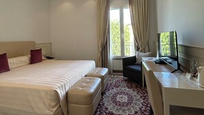 Een hotelkamer met een groot bed, een bureau met een computer en uitzicht op het omliggende landschap.